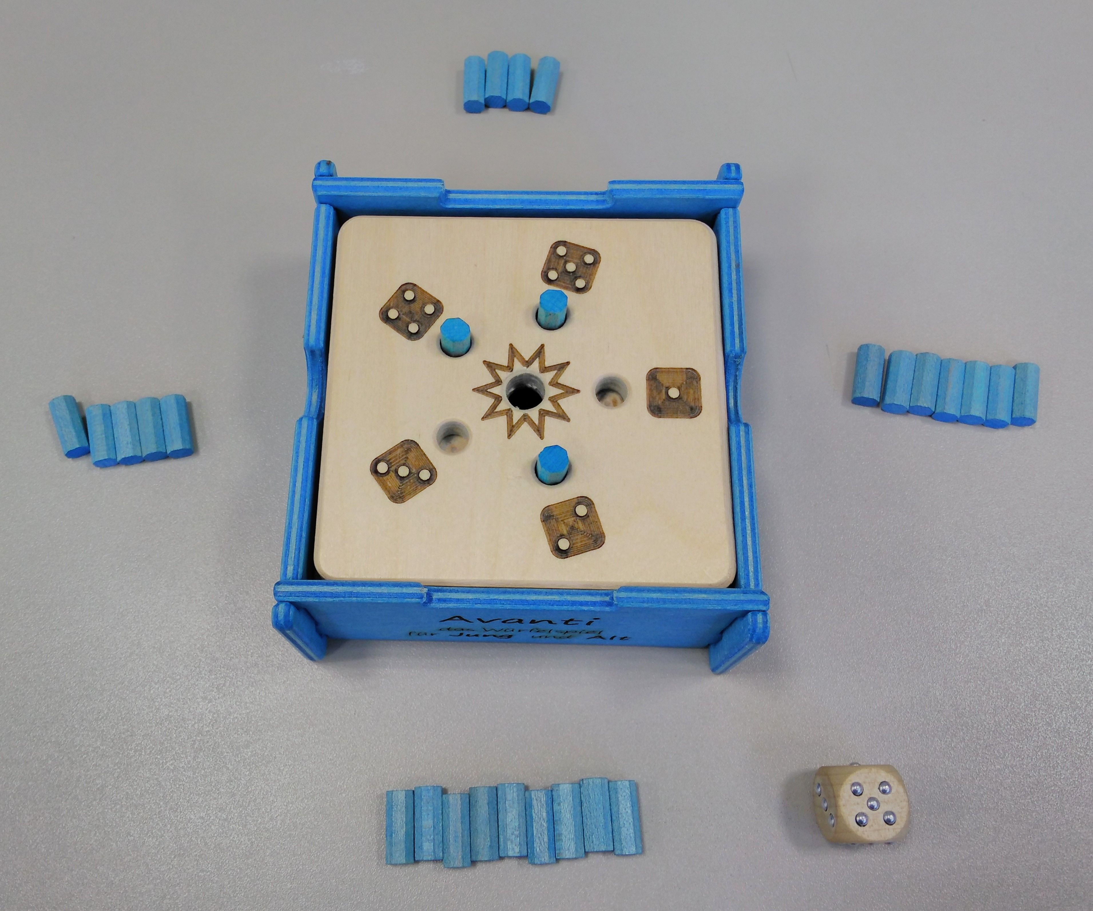 Taktiles Würfelspiel mit 5 Steckplätzen und einem Loch zum Versenken der Spielstifte. An den 4 Seiten liegen blaue Spielstifte, 1 taktiler Würfel
