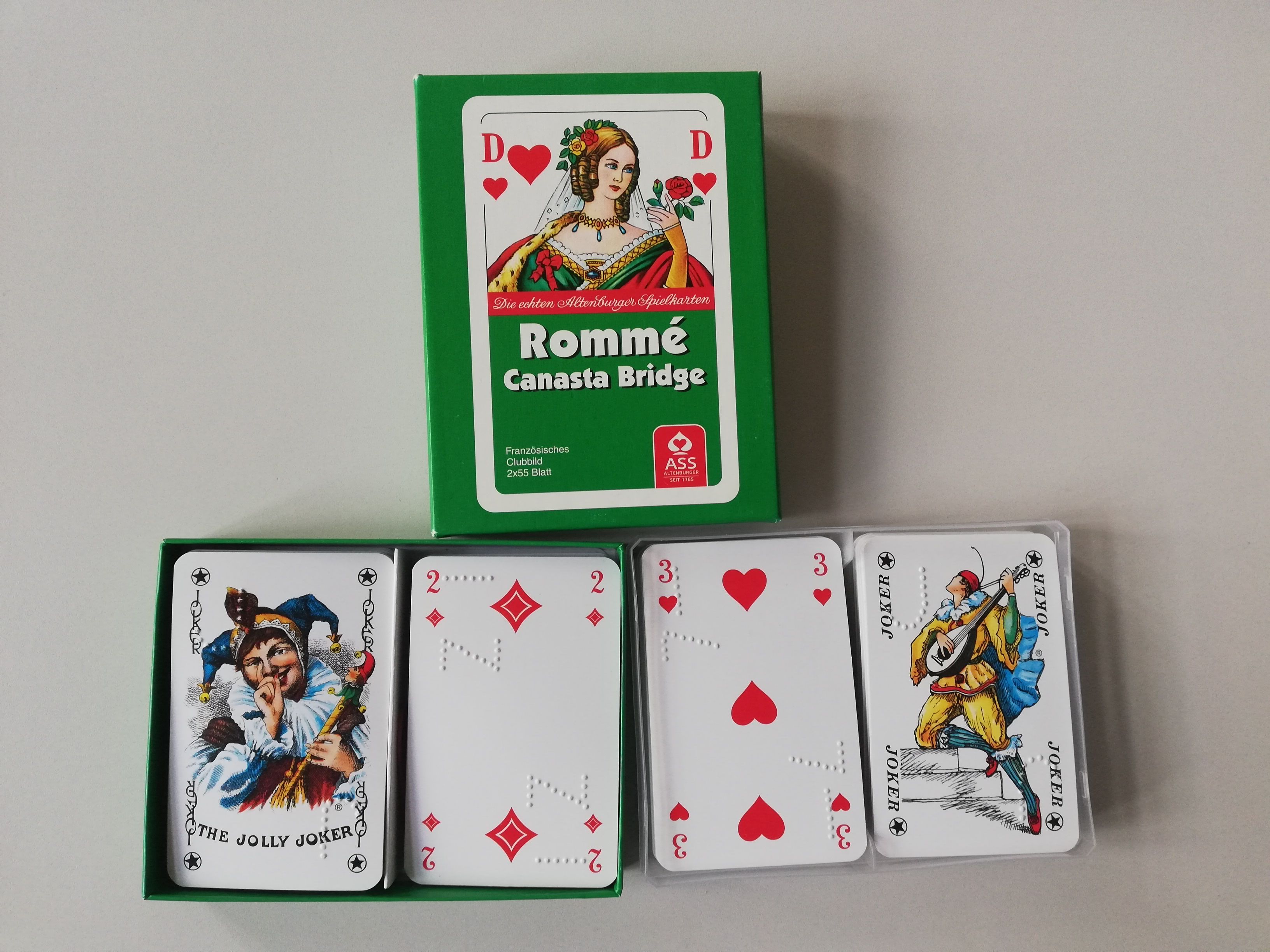 Kartenspiel mit Strichen und Kreisen - zu sehen sind die Spieleschachtel, 2 Jokerkarten, die Karo 2 und die Herz 3