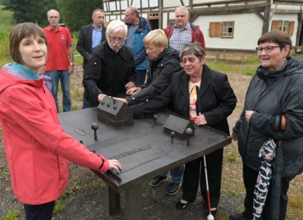 Mehrere Menschen stehen um bzw. Betasten das Bronzemodell der Silberschmelzhütte Sankt Georgen Schneeberg