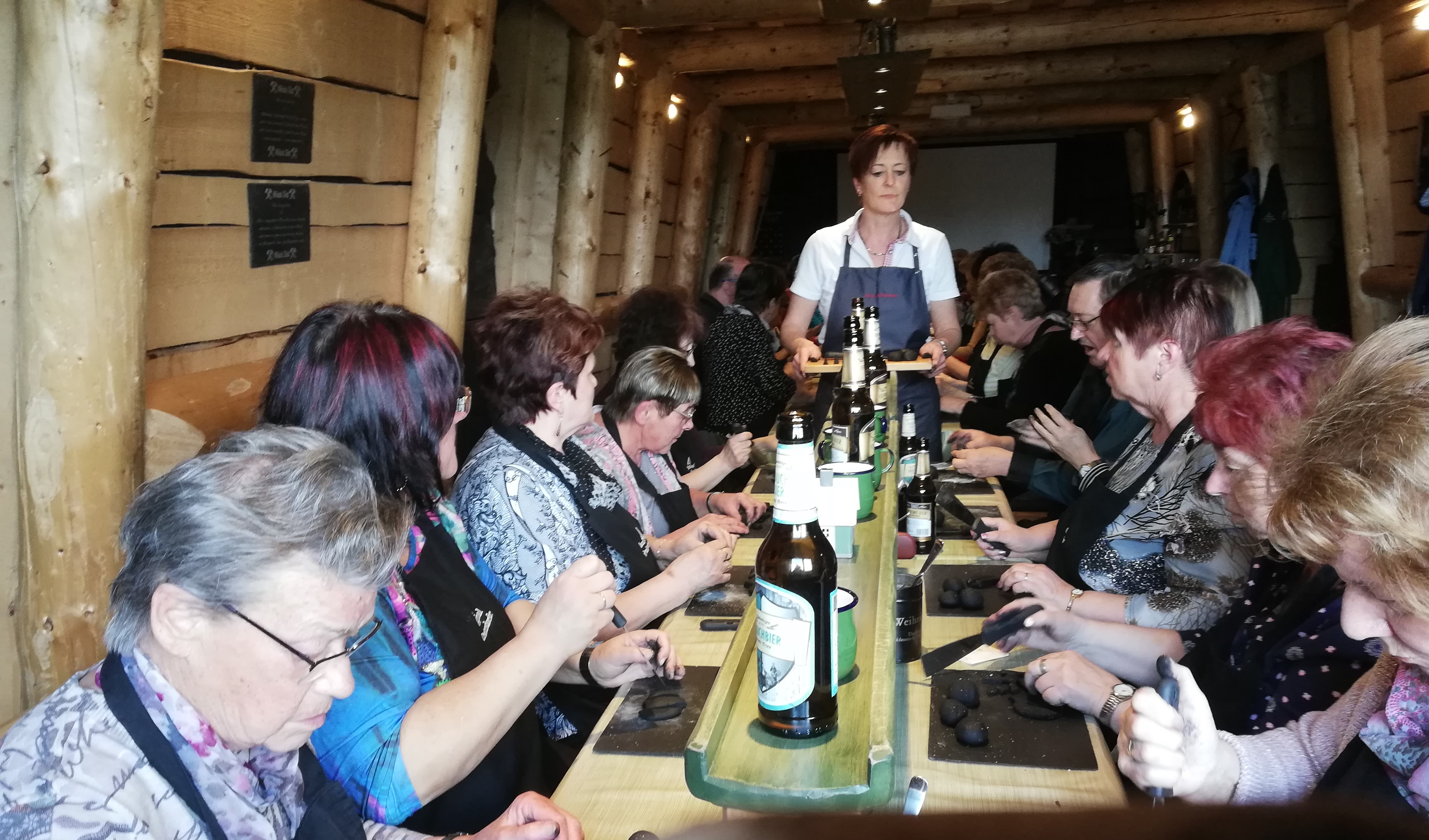 mehrere Personen sitzen an einem langen Tisch und machen Räucherkerzchen selbst