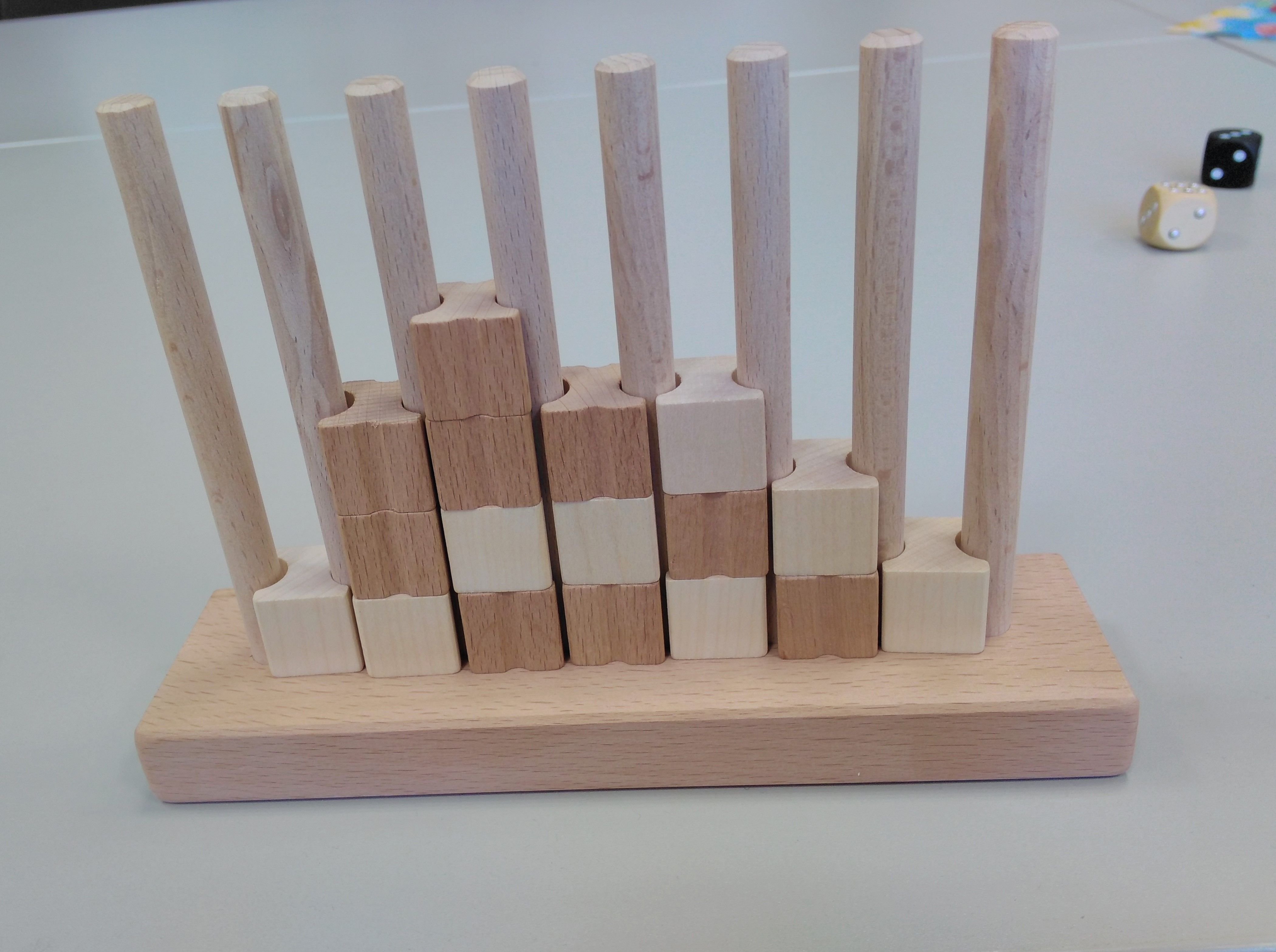 Zwischen den 8 Stangen stecken Spielsteine mit 2 verschiedenen Oberflächen.